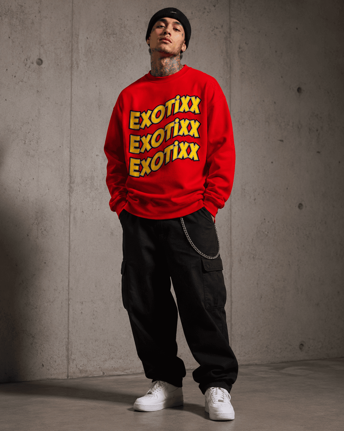 Model in red Mr. Exotixx triple-wordmark crewneck and black cargo pants against a concrete wall