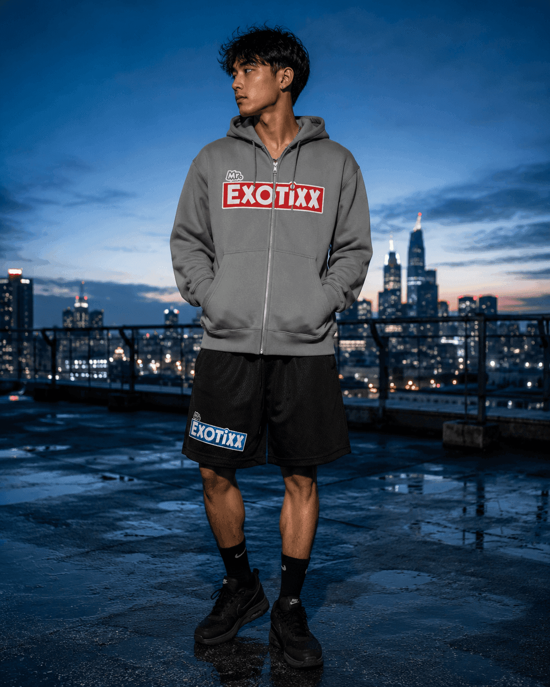 Figure in the Mr. Exotixx zip hoodie against a rooftop skyline at night